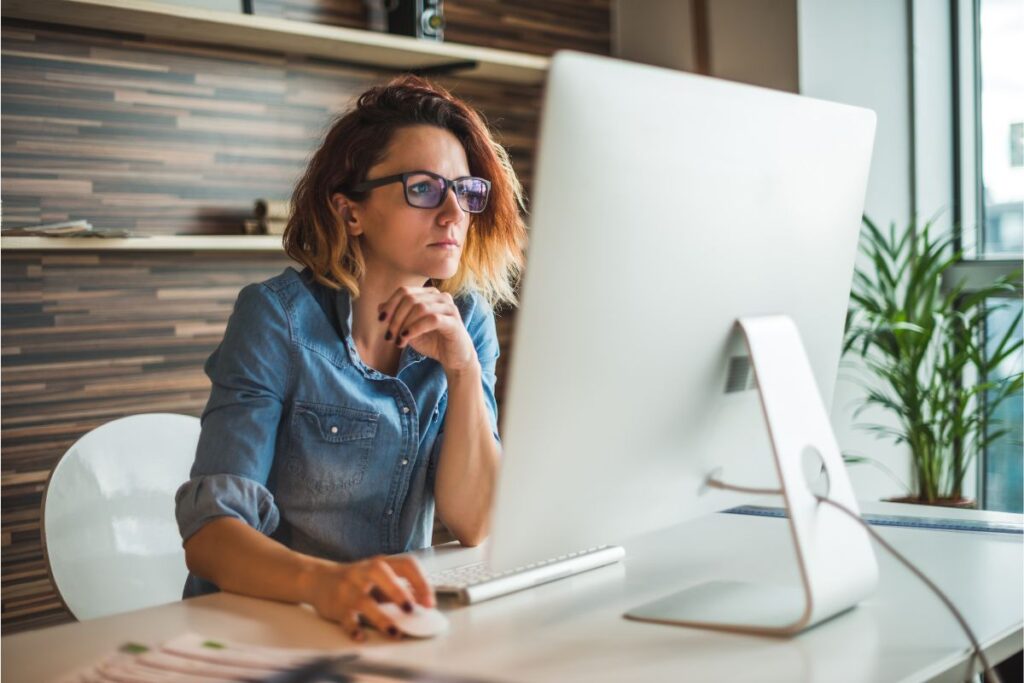 Junge Unternehmerin plant ihre Nischenstrategie am Computer - authentisches Arbeitsplatz-Setting